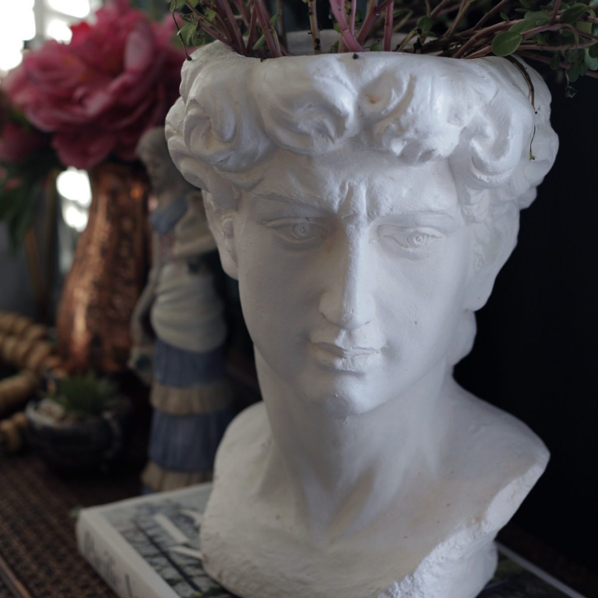 white statue of a bust with plant